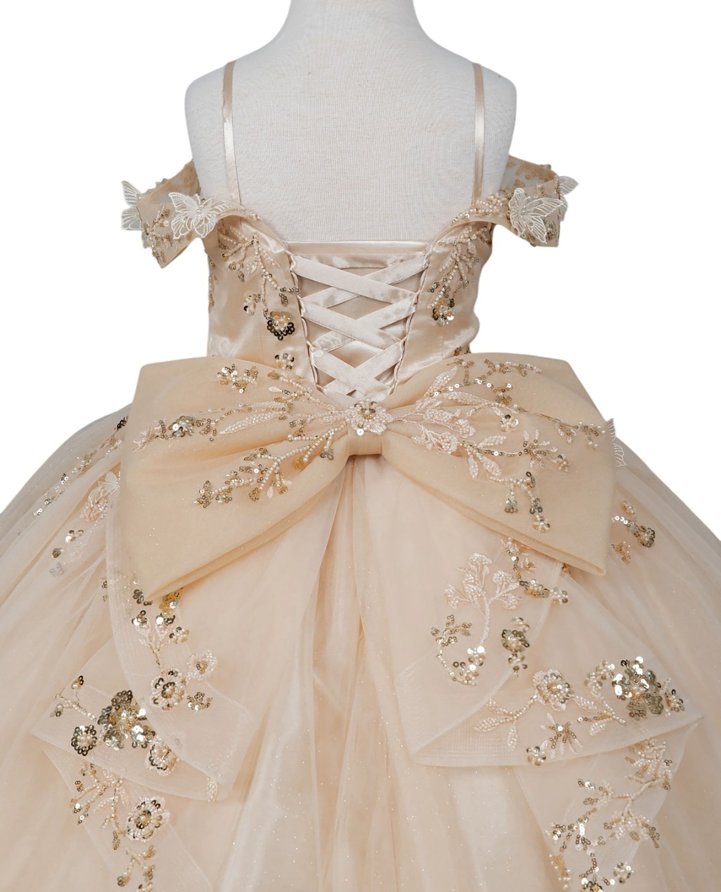 Beige evening gown with floral embellishments on a mannequin against a white background