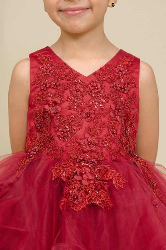 Child wearing a burgundy embroidered dress with a beige background