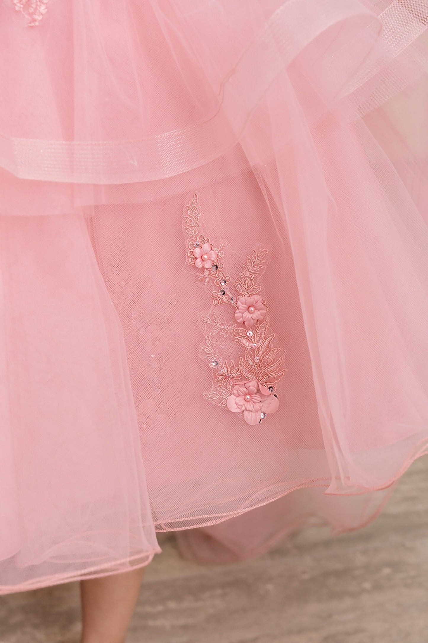 Close-up of a dusty rose dress with floral embroidery on a blurred background
