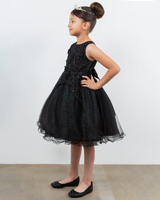 Young girl wearing a black dress with floral details against a white background