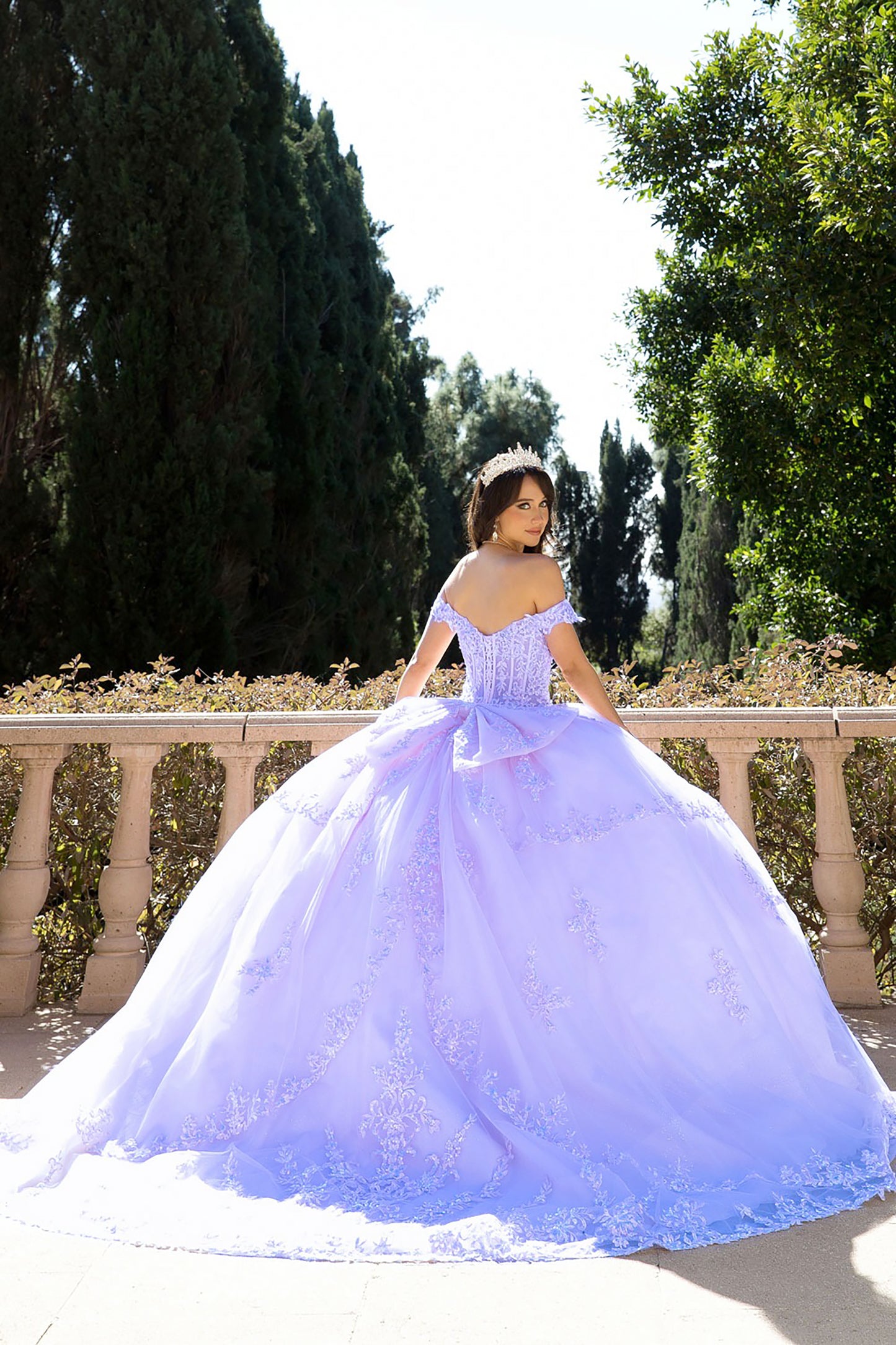 girl in a lilac quinceanera ball gown dress standing outdoors with trees in the background