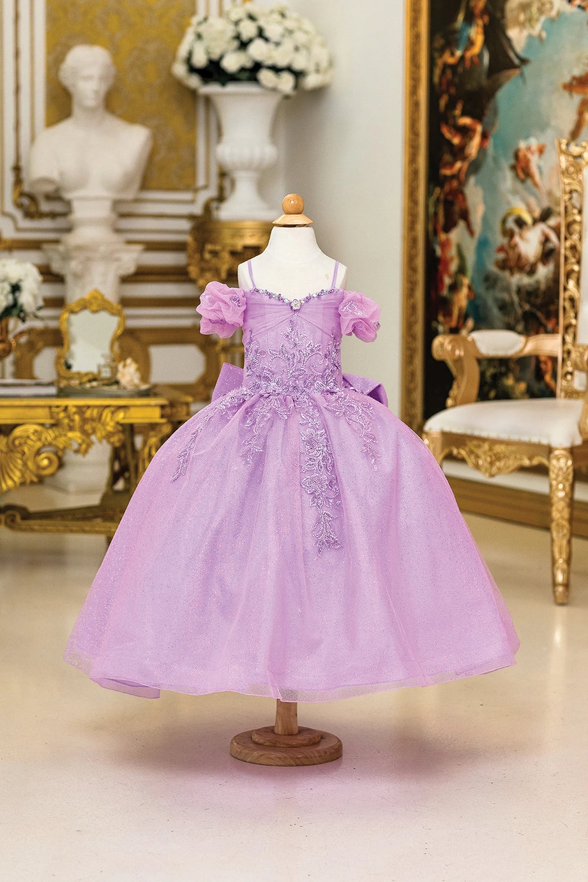 In full view, the Lilac mini quinceañera dress shows puff sleeves and lace appliqué over the lilac bodice.