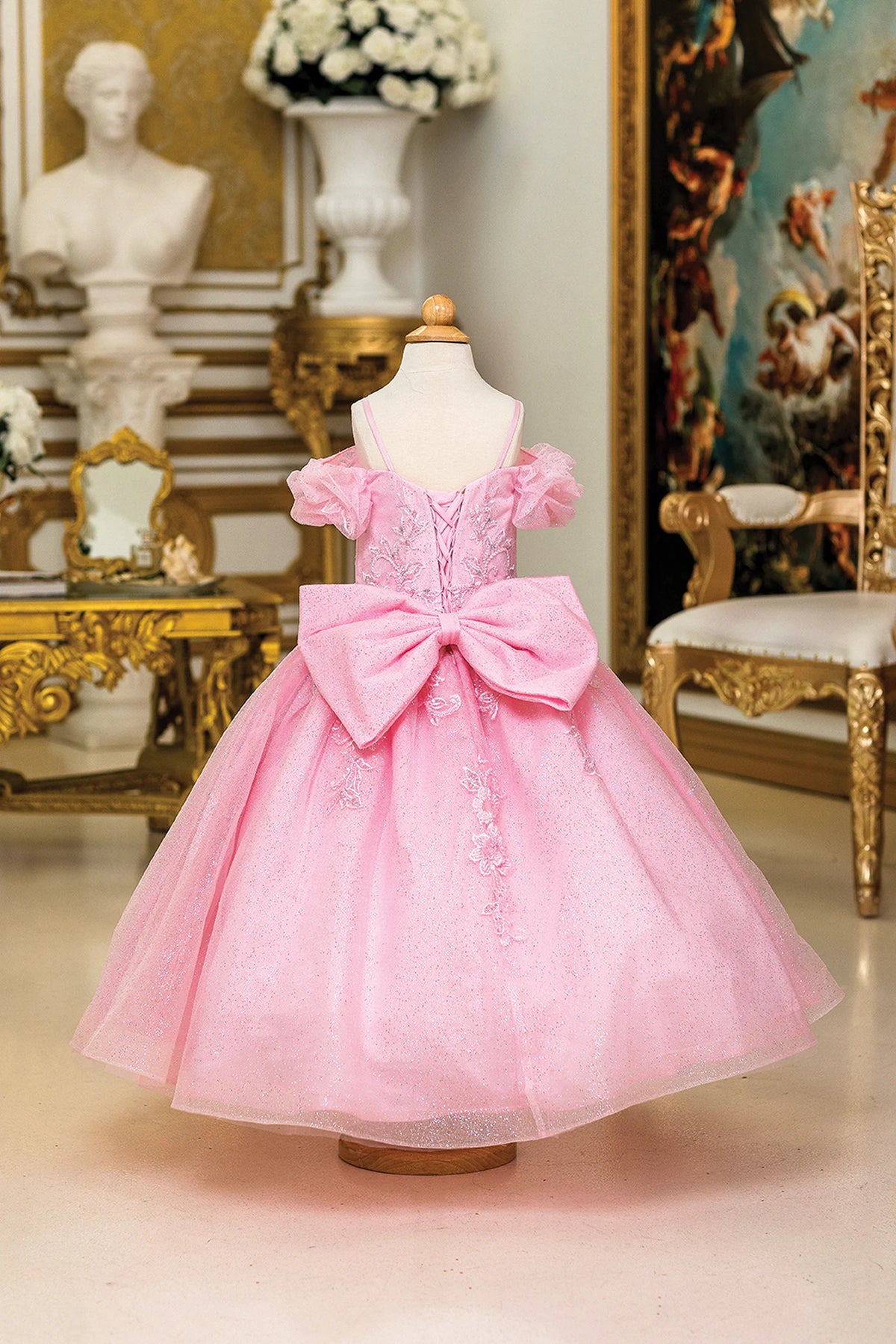 Finished with a large bow, the Pink mini quinceañera ball gown shows its lace-up back.