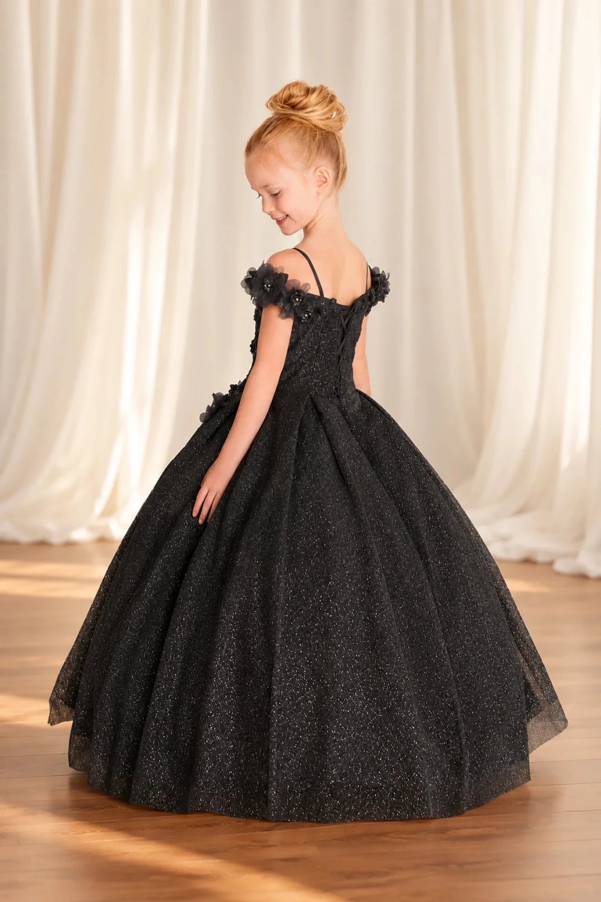 a black off-the-shoulder ball gown with a sparkly textured tulle skirt and lace up back