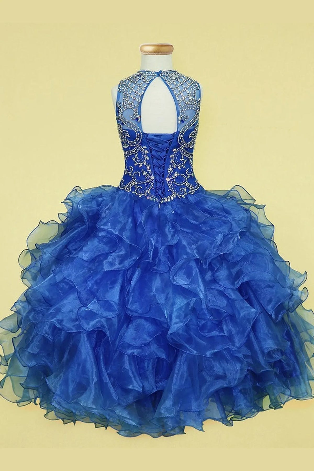 From behind, the Royal Blue mini quince dress displays its lace-up finish and playful tiered organza ruffle skirt.