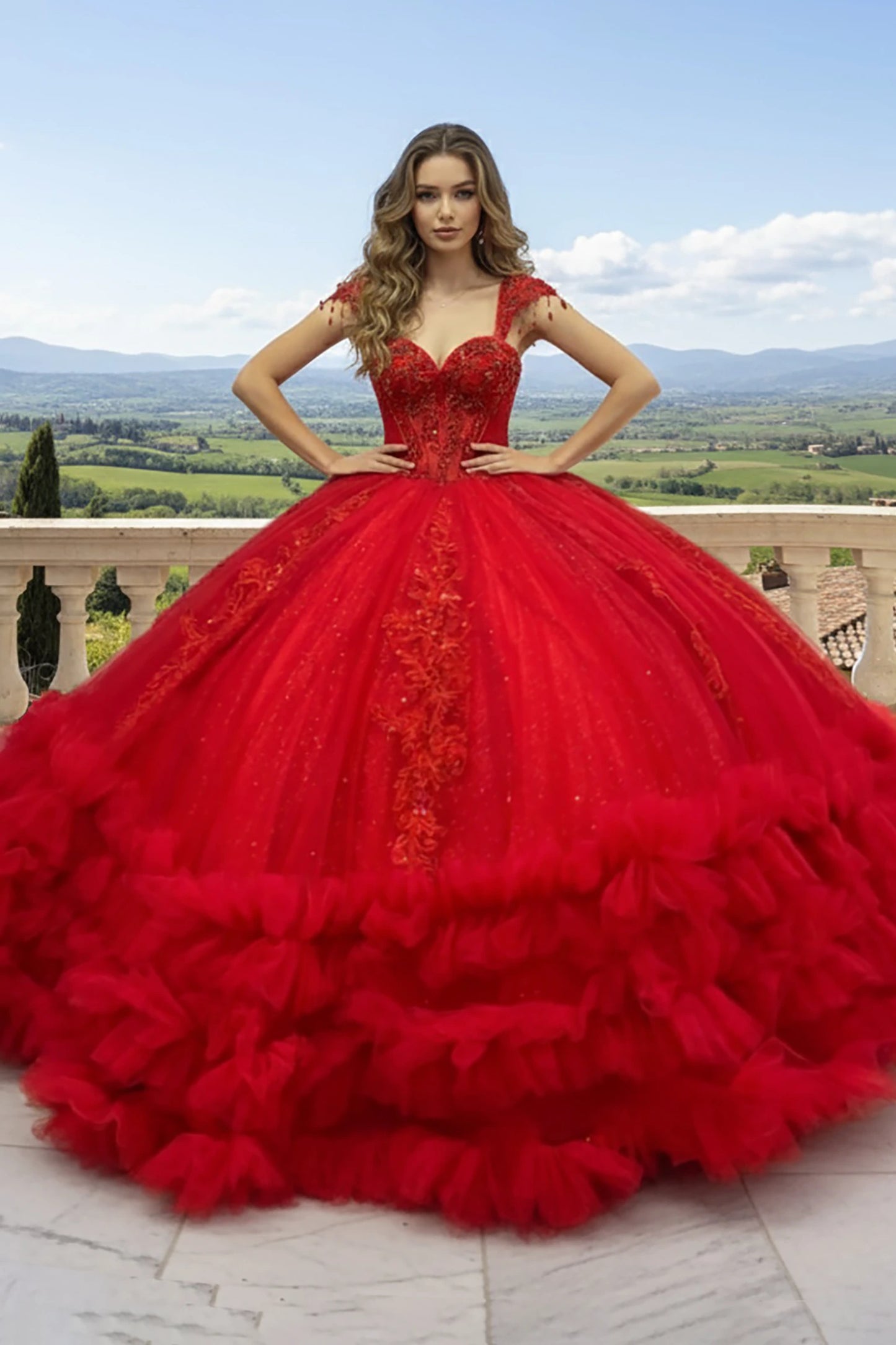 Red ball gown with intricate detailing such as Full layered tulle skirt with glitter finish, vertical lace appliqués, and ruffled hem standing outdoor