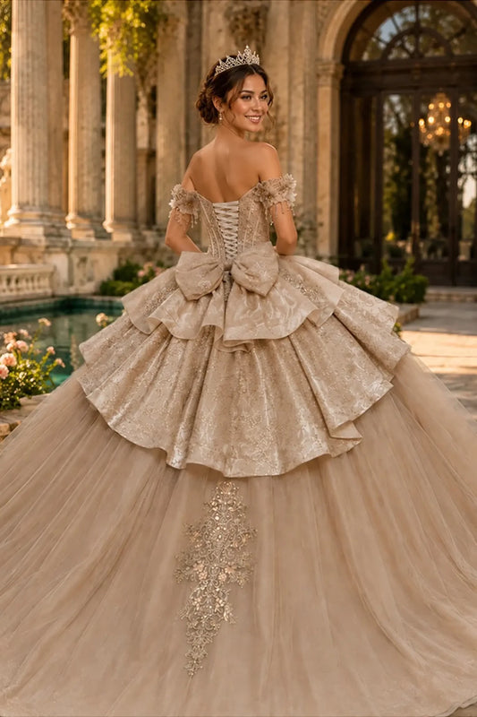 Champagne quinceañera ball gown completed with lace-up back, oversized bow and dramatic sweeping train