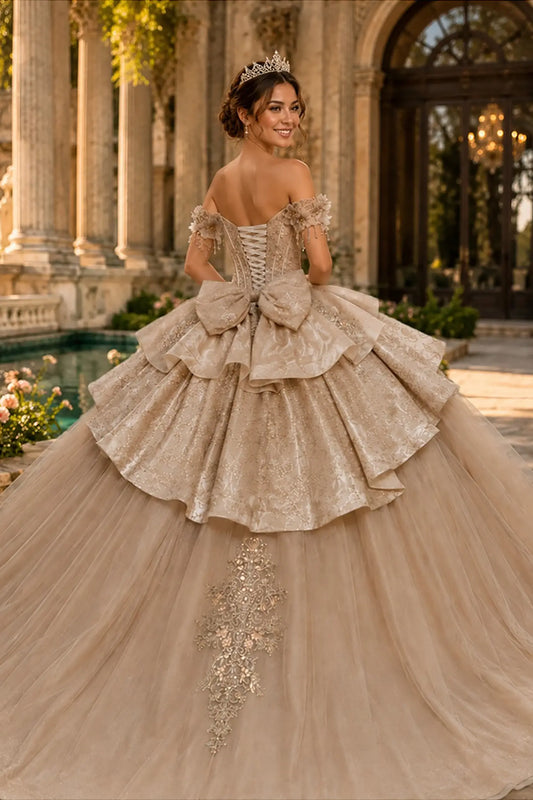 Champagne quinceañera ball gown completed with lace-up back, oversized bow and dramatic sweeping train