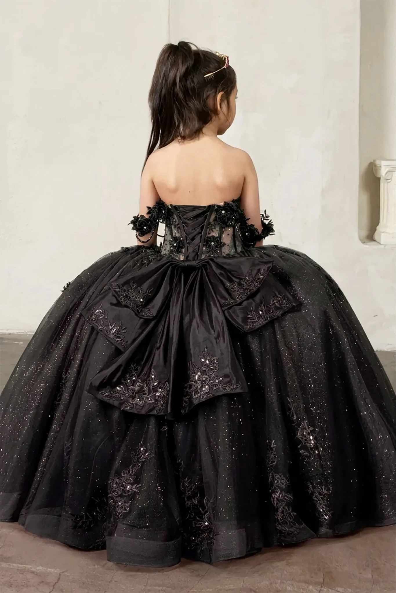 A black, ornate mini quince dress with large big back bow.