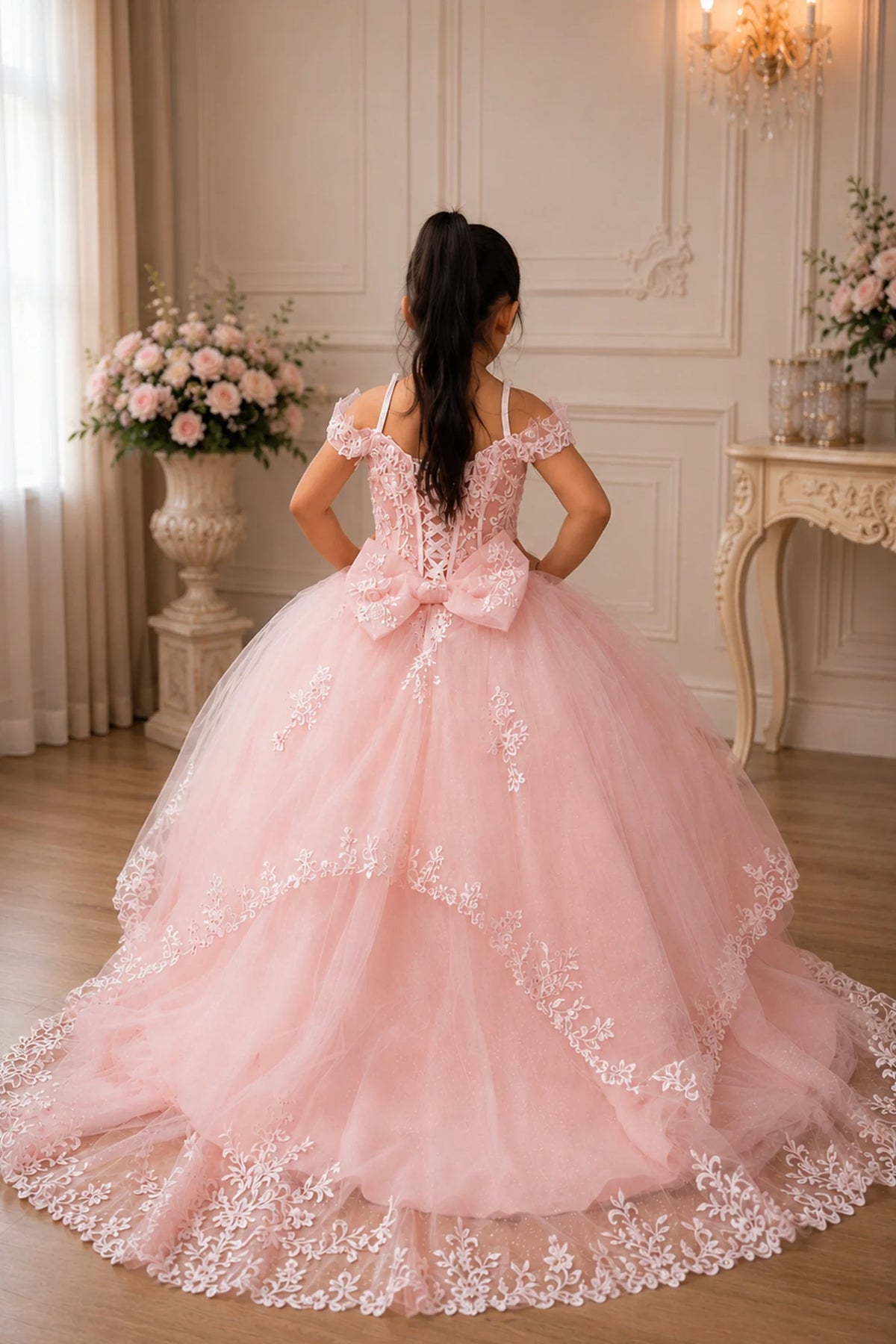 The reverse view reveals, the Blush Pink mini quince dress displays its lace-up finish and full tulle skirt with a large bow at the back.