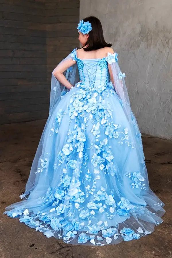 Kid standing back-facing in light blue ball gown with lace-up closure, dramatic two-tone tail, and matching cape cascading over full skirt