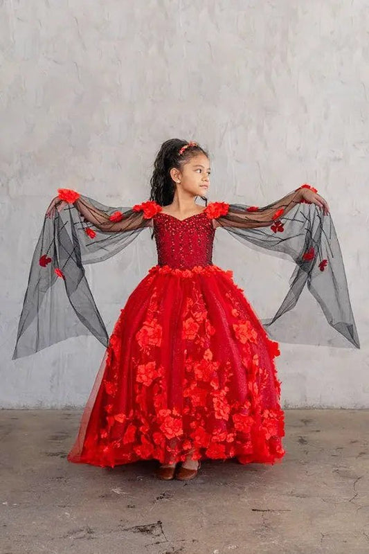 Kid standing front-facing in red ball gown with lace-up closure, dramatic two-tone tail, and matching cape cascading over layered tulle skirt