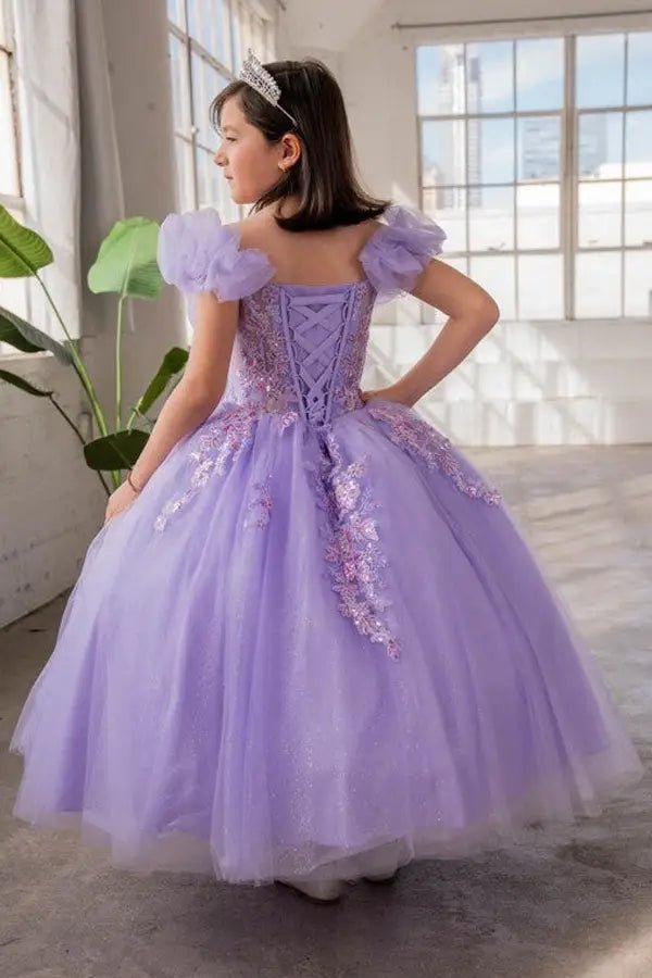 Kid standing back-facing in lilac ball gown with lace-up closure, illusion sweetheart bodice, and cascading flowing skirt