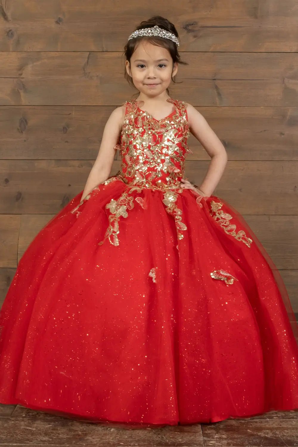 Kid standing front-facing in stunning red ball gown with 3D floral appliqué bodice and glitter tulle layered skirt