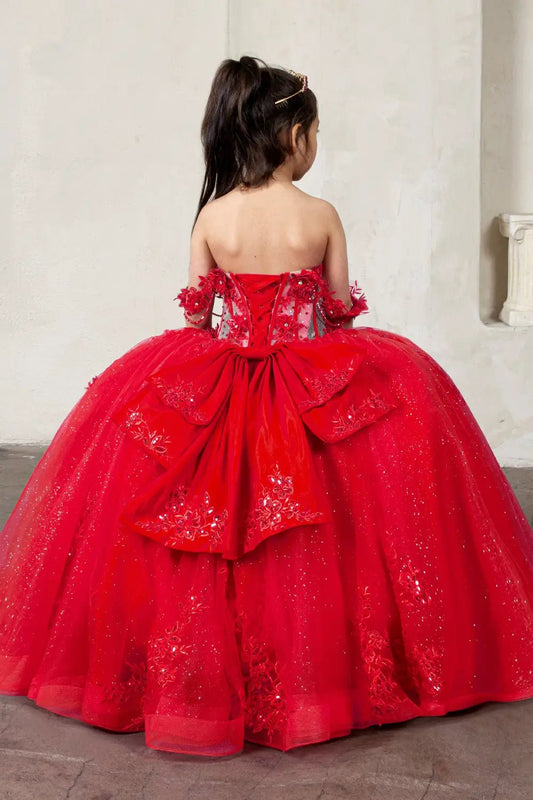 Kid standing back-facing in red ball gown with lace-up closure, detachable bow accent, crystal beading, and cascading glitter tulle skirt