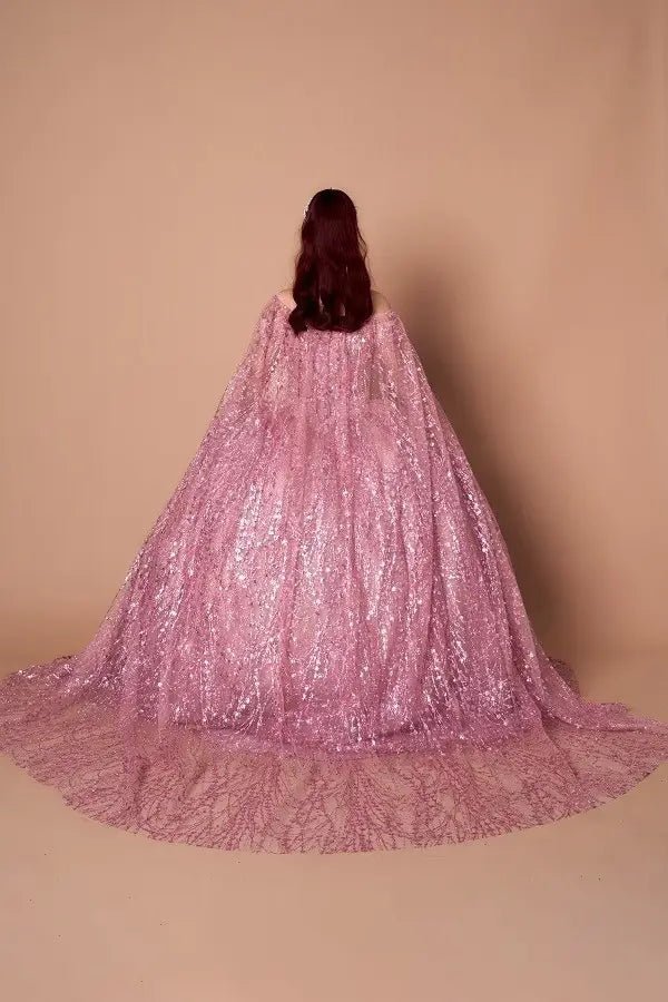Back-Facing of a woman wearing Dusty rose formal dress featuring open back sweep train and soft cape detail