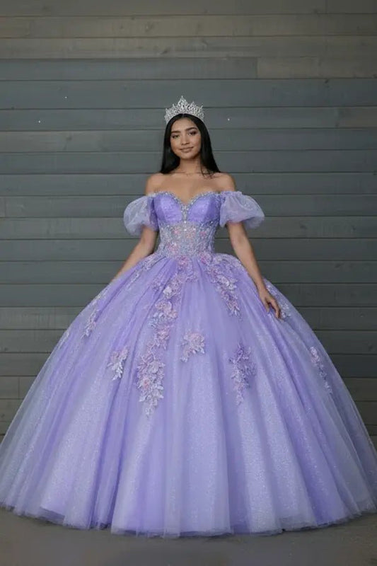 Front-Facing of a woman wearing Lilac gown featuring lace-up back flowing glitter tulle skirt and detachable cape detail