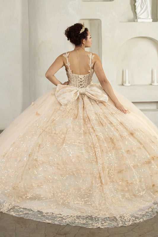 Back-Facing of a woman wearing Champagne formal gown featuring detachable bow accent layered skirt and flowing silhouette