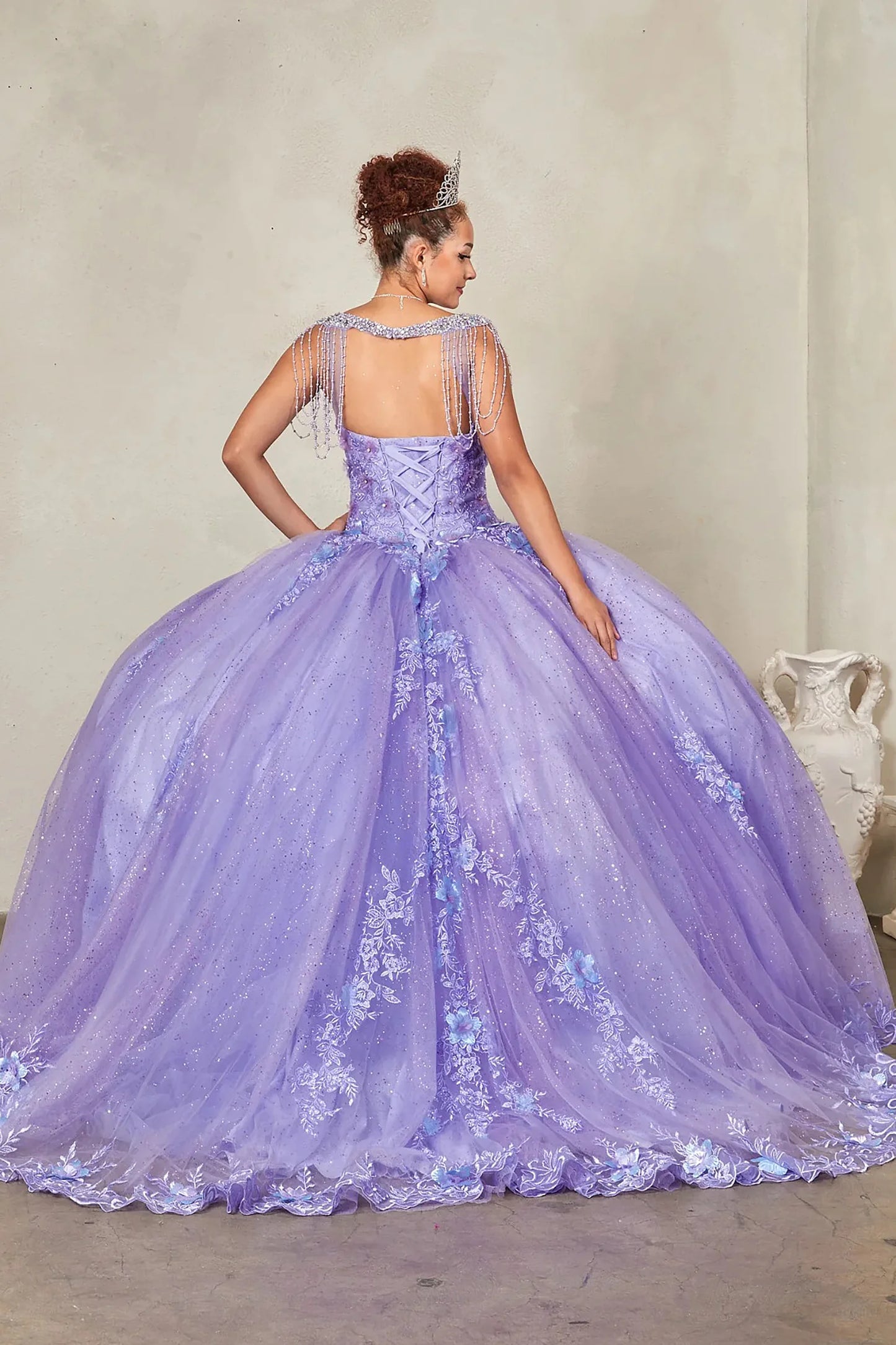 Lilac quinceañera ball gown extending into graceful train with lace appliqués accenting bead-fringed