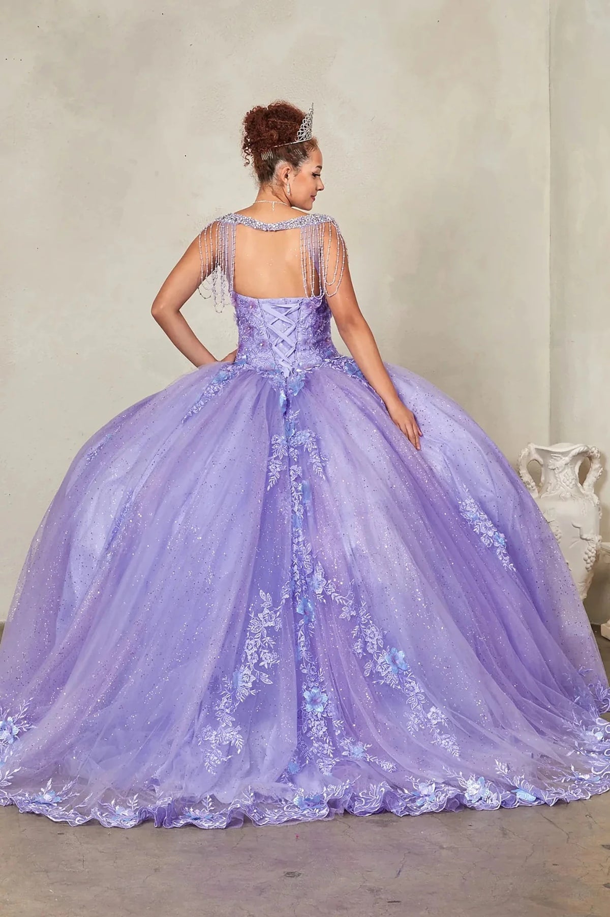 Lilac quinceañera ball gown extending into graceful train with lace appliqués accenting bead-fringed