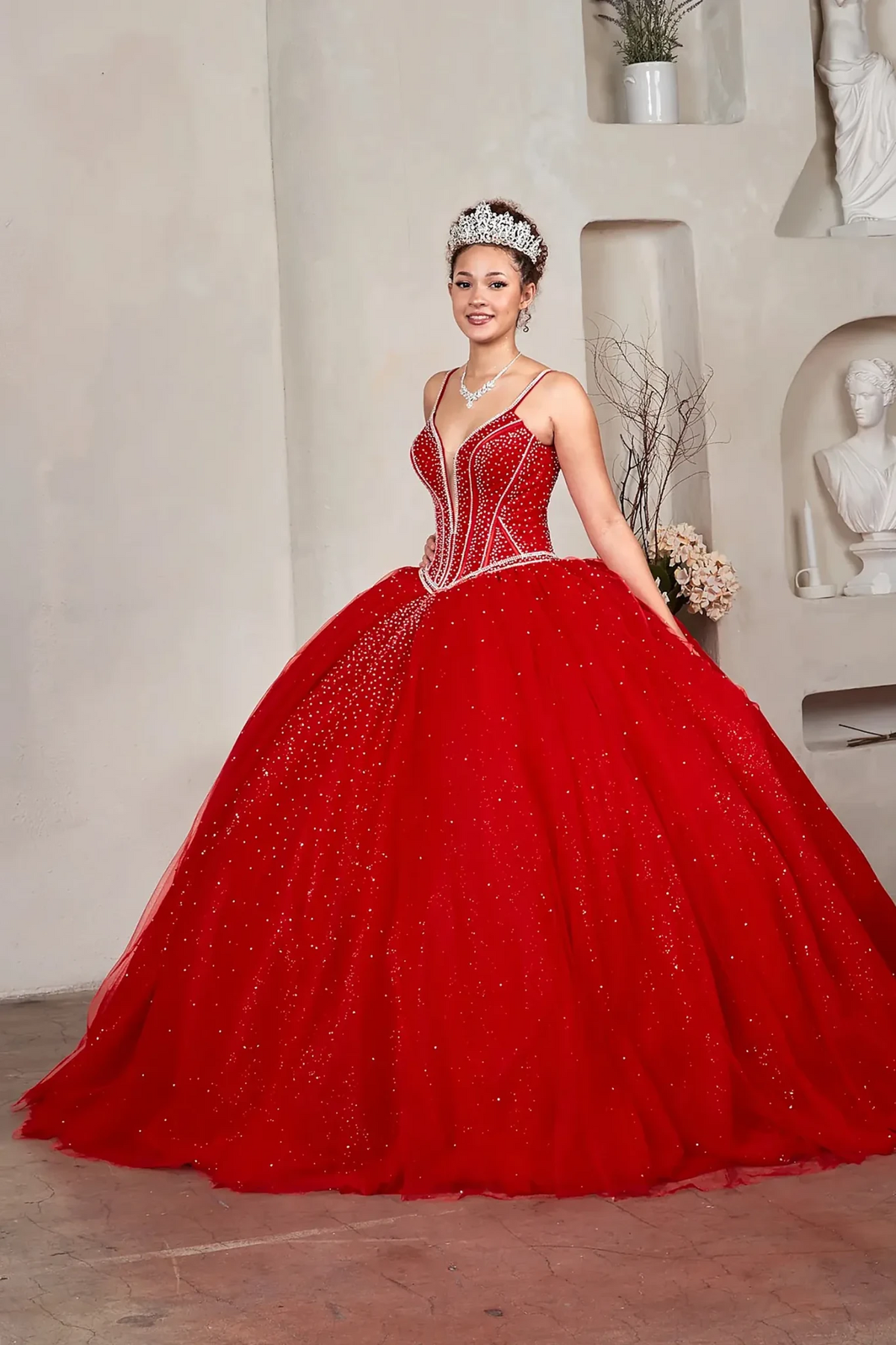 Red quinceañera ball gown with crystal beaded corset, V‑neckline, spaghetti straps and glitter tulle skirt