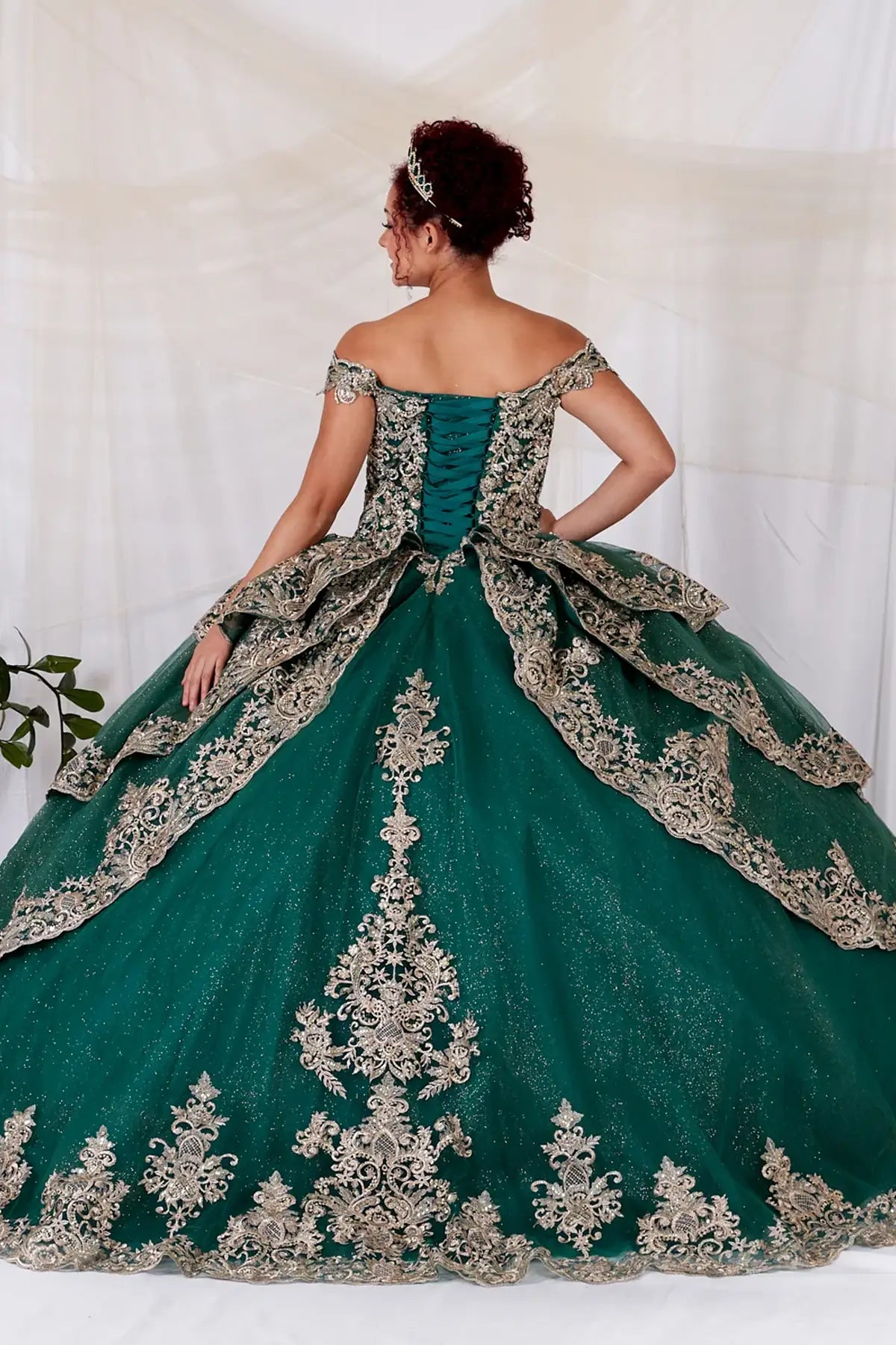 Back-Facing of a woman wearing Emerald formal gown featuring structured back multi-layer skirt and elegant design