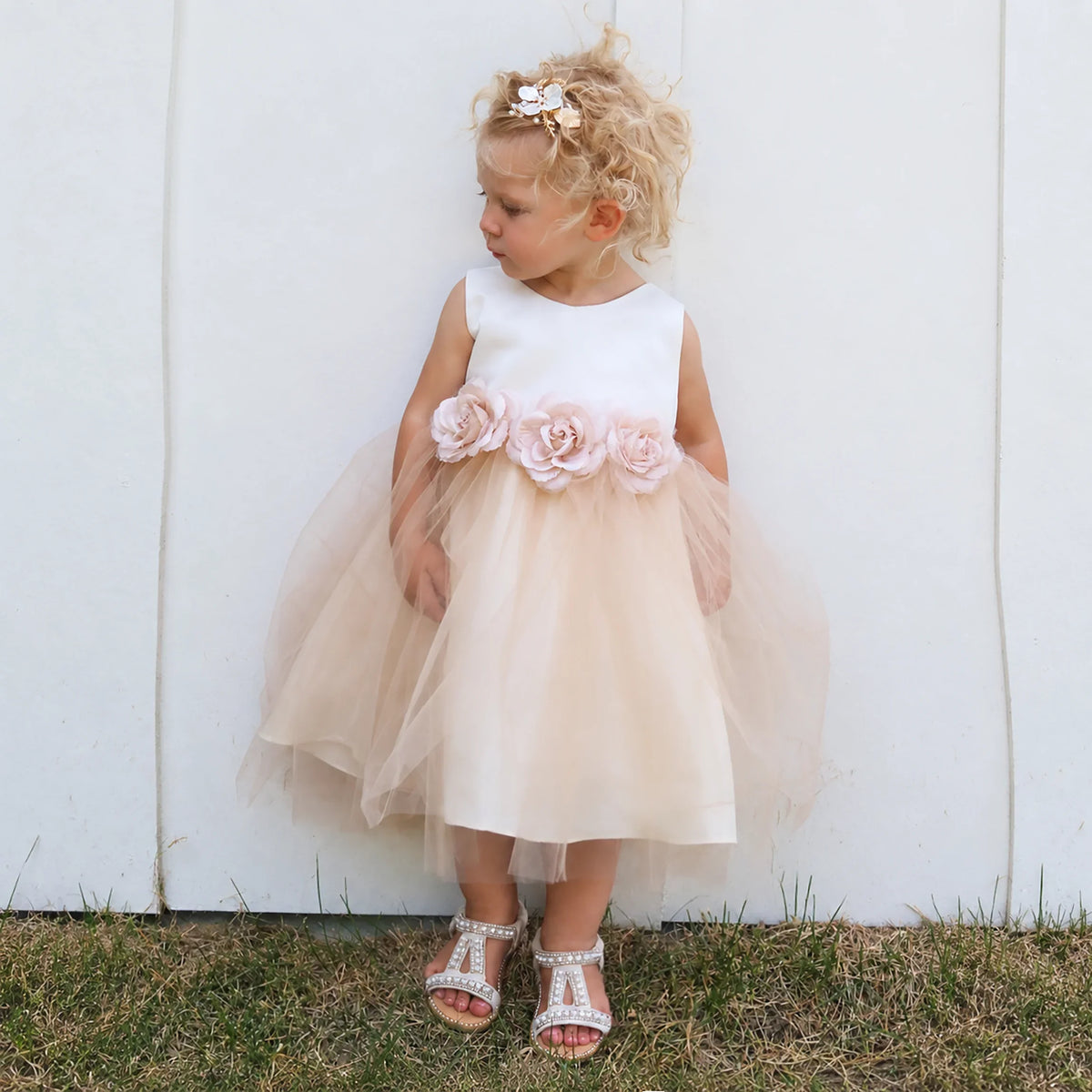Girl wearing a blush tulle flower girl dress with floral details