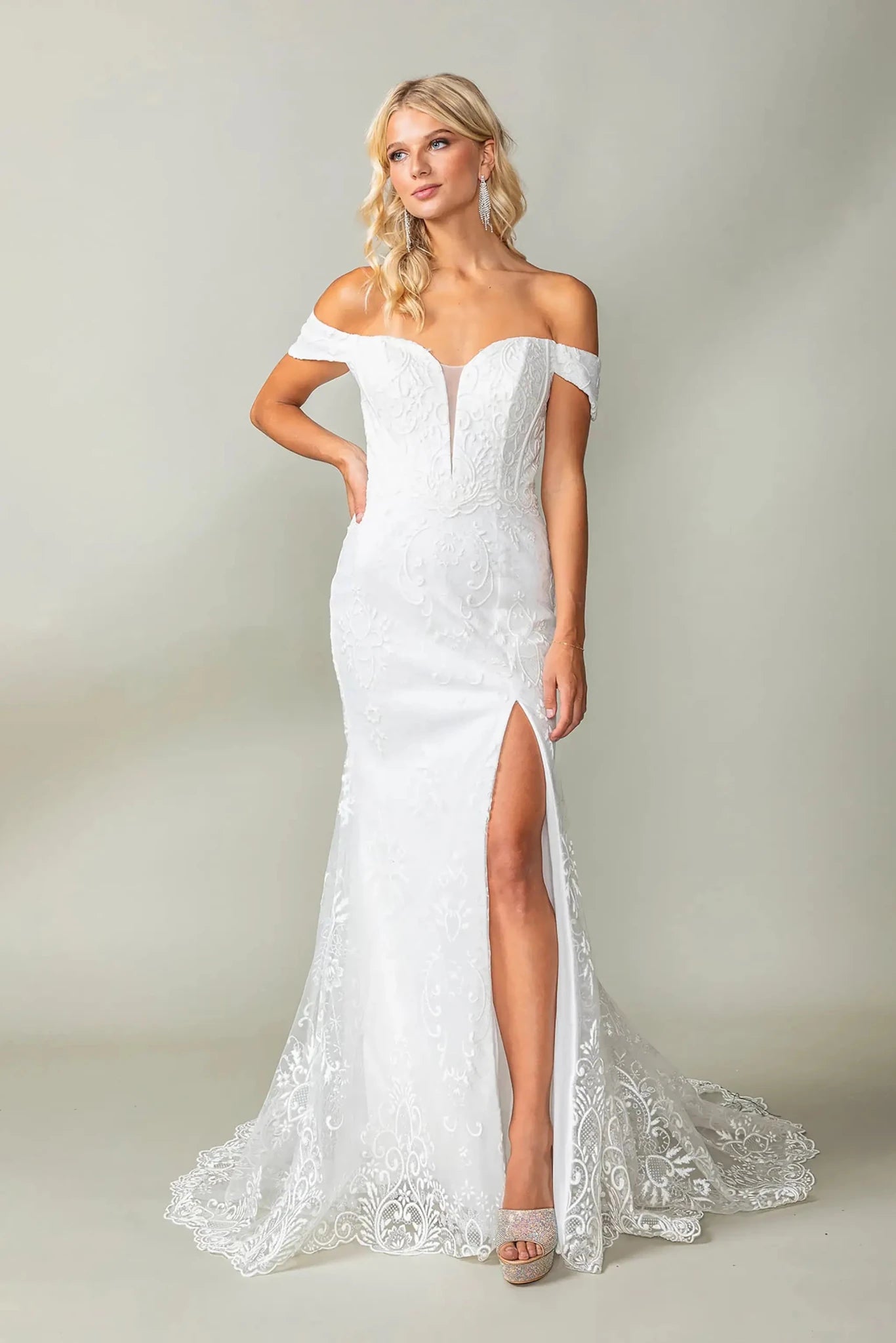 Woman in Off white lace mermaid wedding gown with off-shoulder neckline and detailed train.