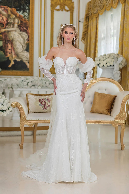 Woman in Off white mermaid wedding dress with sheer lace bodice and puff sleeves.