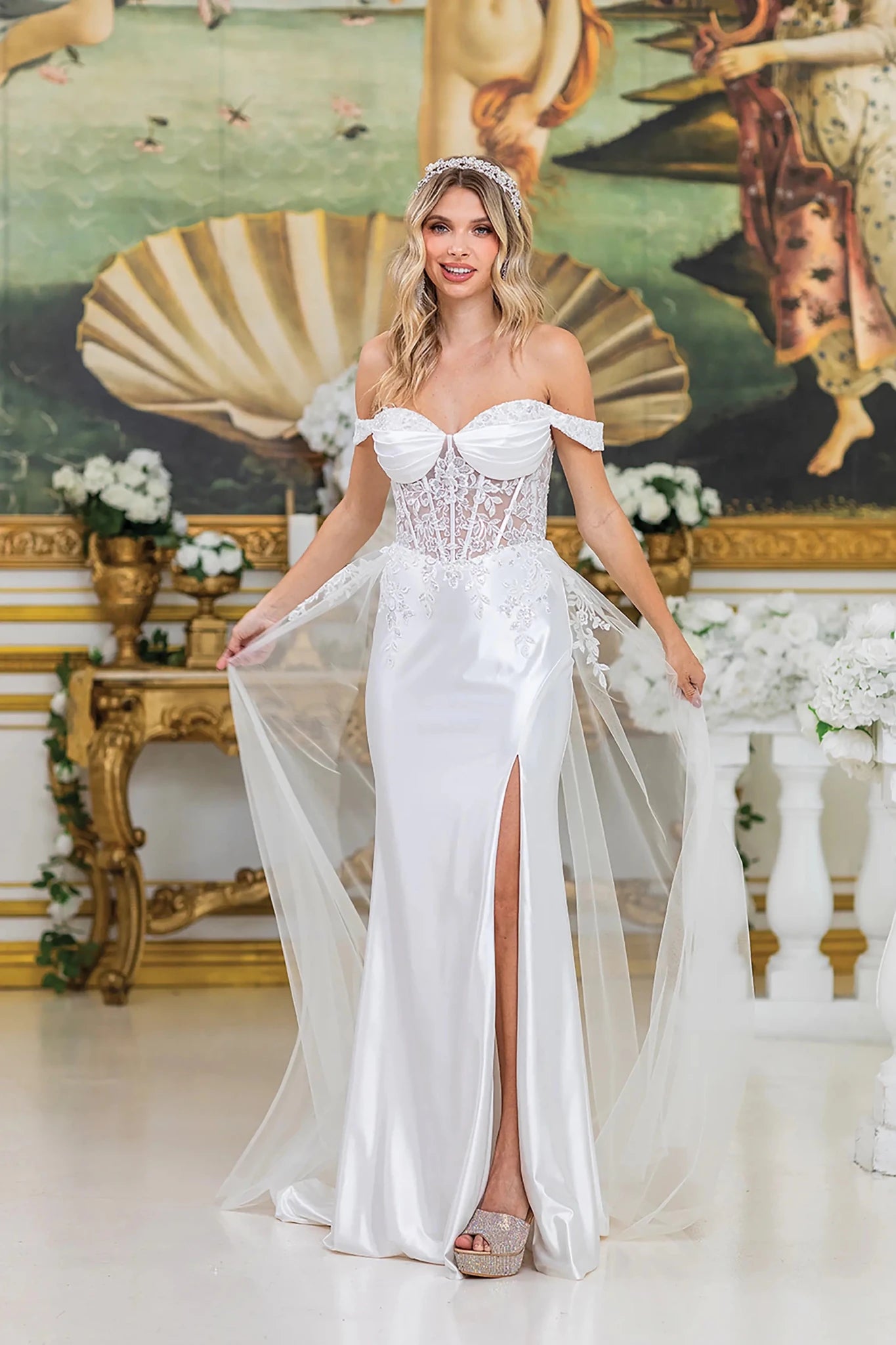 Woman in Off white off-shoulder wedding dress with lace-up back and flowing train.