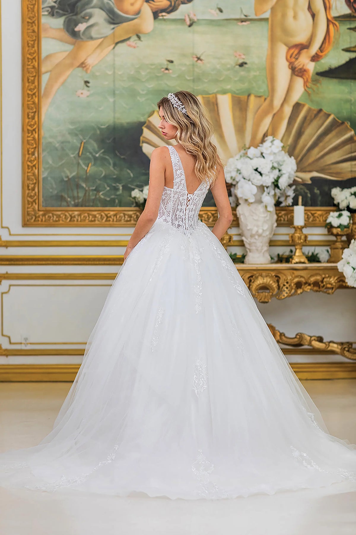 Revealing a lace-up back above its flowing train, this Off-White wedding dress is shown from the back.