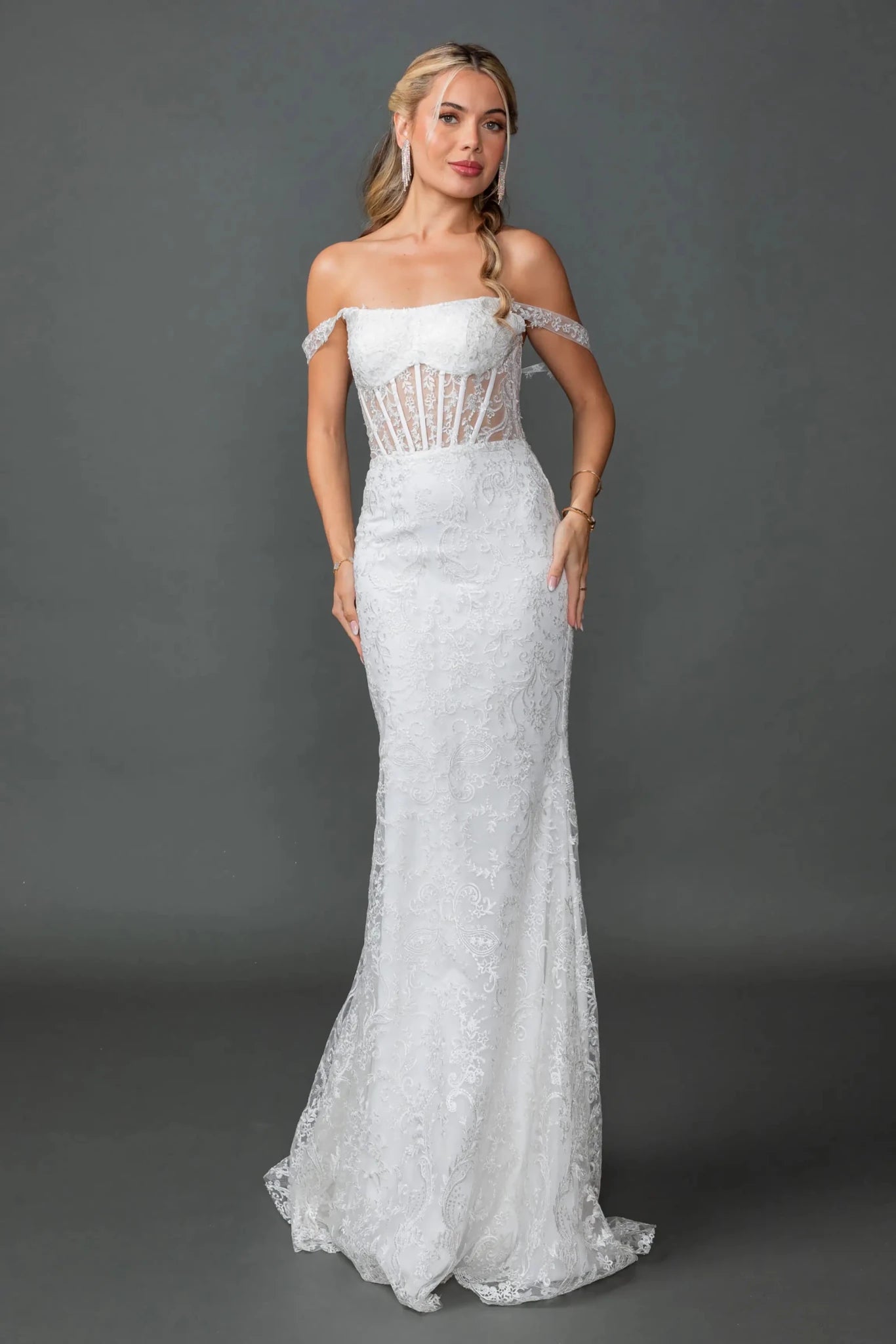 Woman in Off white off-shoulder mermaid wedding gown with sheer corset and lace embroidery.