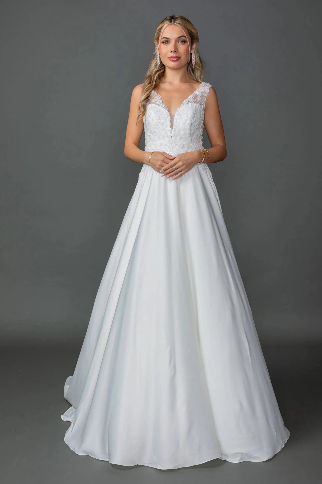 Woman in Off white A-line wedding dress with V-neck lace bodice and satin skirt.