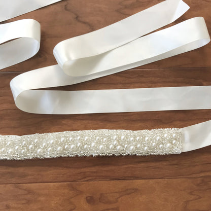 Intricate features stand out across ivory pearl satin flower girl sash belt.