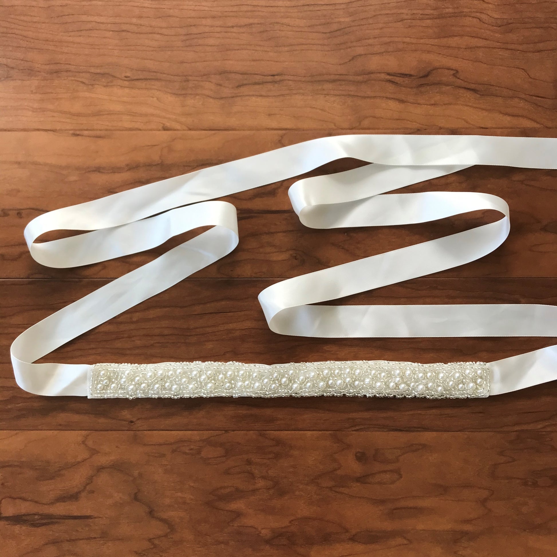 Ivory and white pearl satin flower girl sash belt, close-up, full view, embellishment detail.