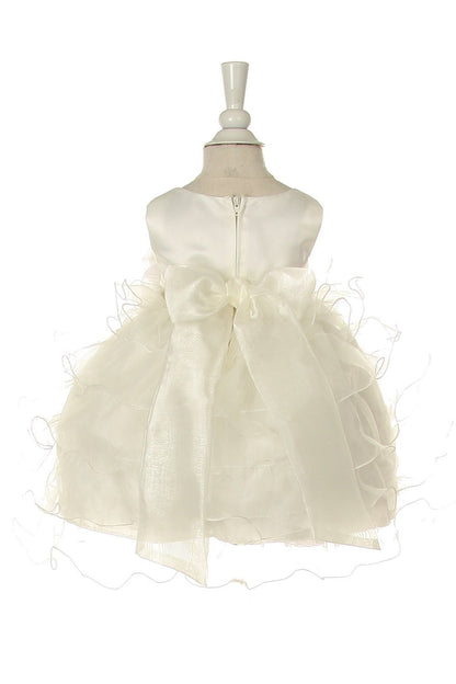 Back view of Little girl wearing ivory rose dress at wedding or christening event posing elegantly