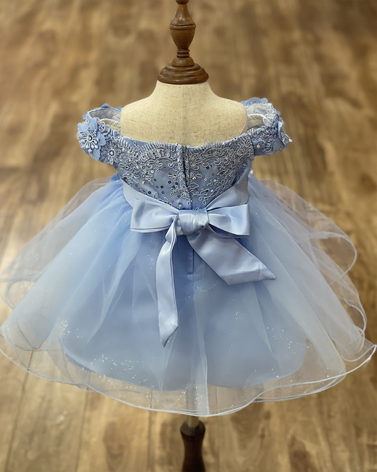 Light blue dress with floral embellishments on a mannequin against a wooden background