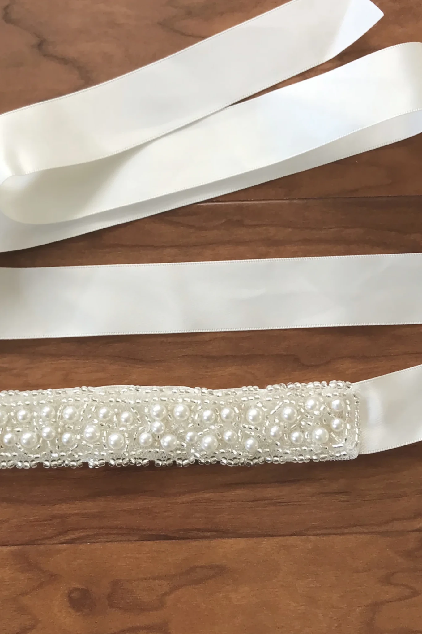 Ivory satin sash belt embellished with a row of white faux pearls