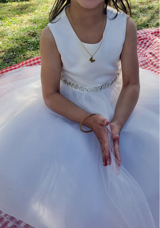 kid wearing a white satin and tulle dress with pearl and rhinestone belt