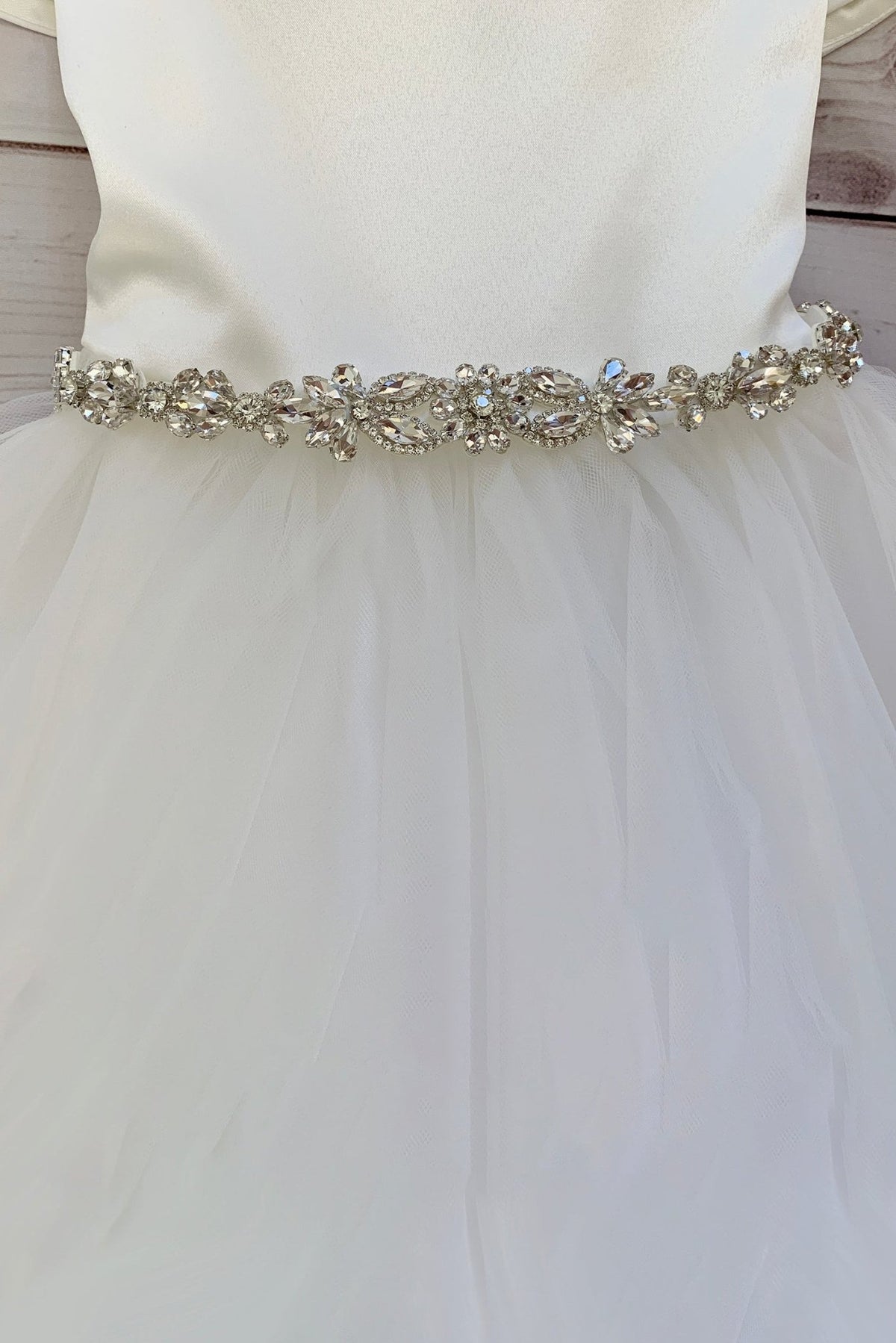 White flower girl dress with a decorative clear rhinestone belt.
