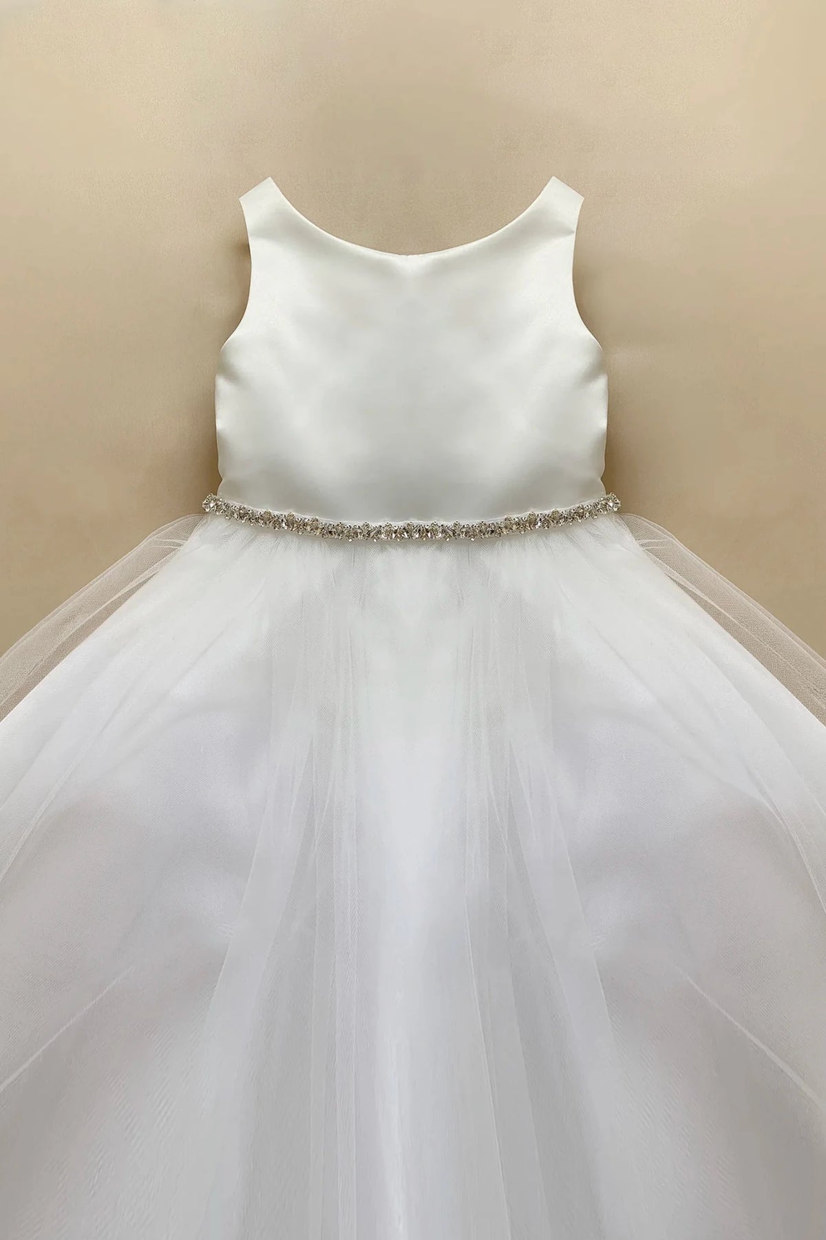 White sleeveless flower girl dress with a satin bodice, a rhinestone waistband, and a voluminous tulle skirt.