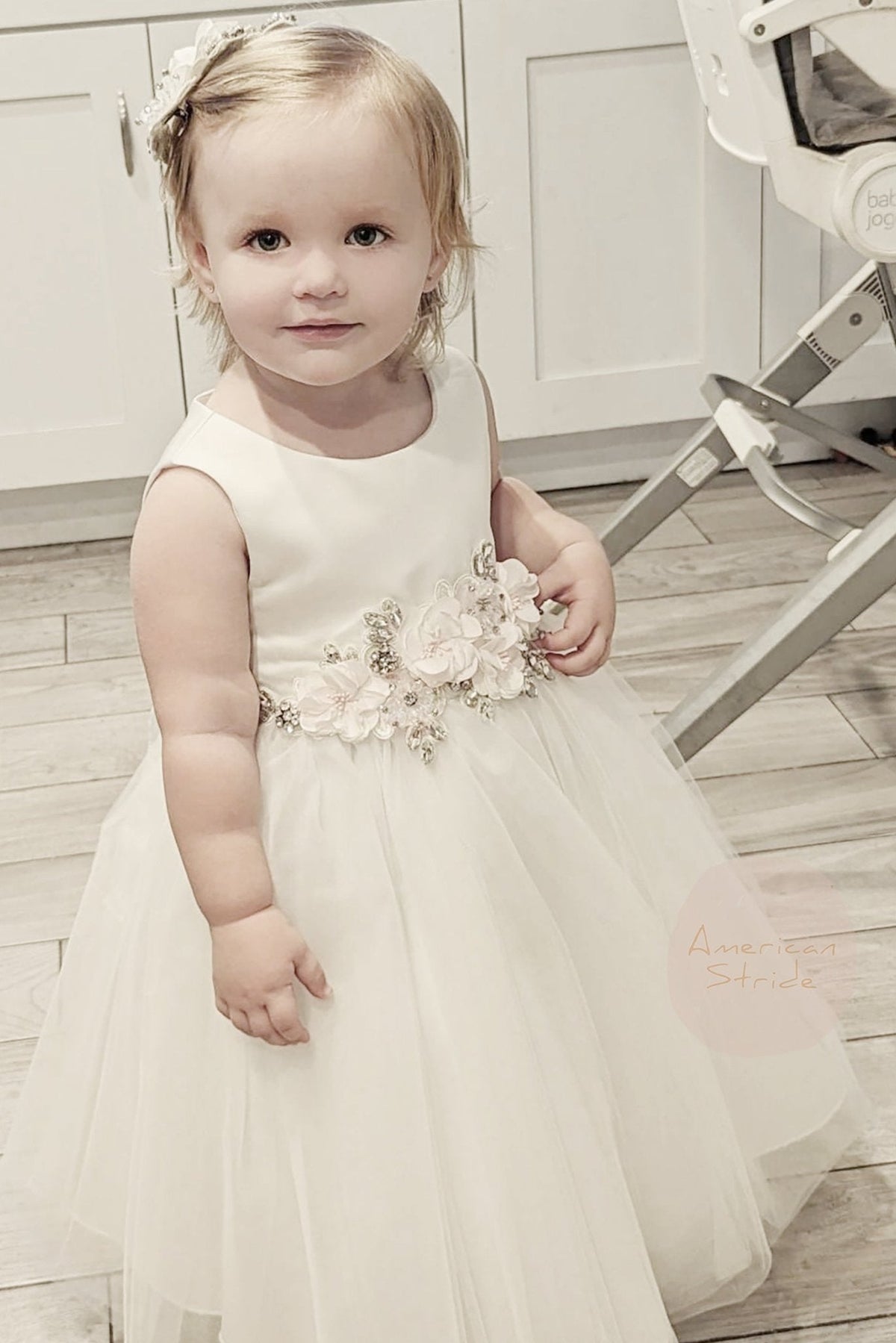 A white flower girl dress with floral details.