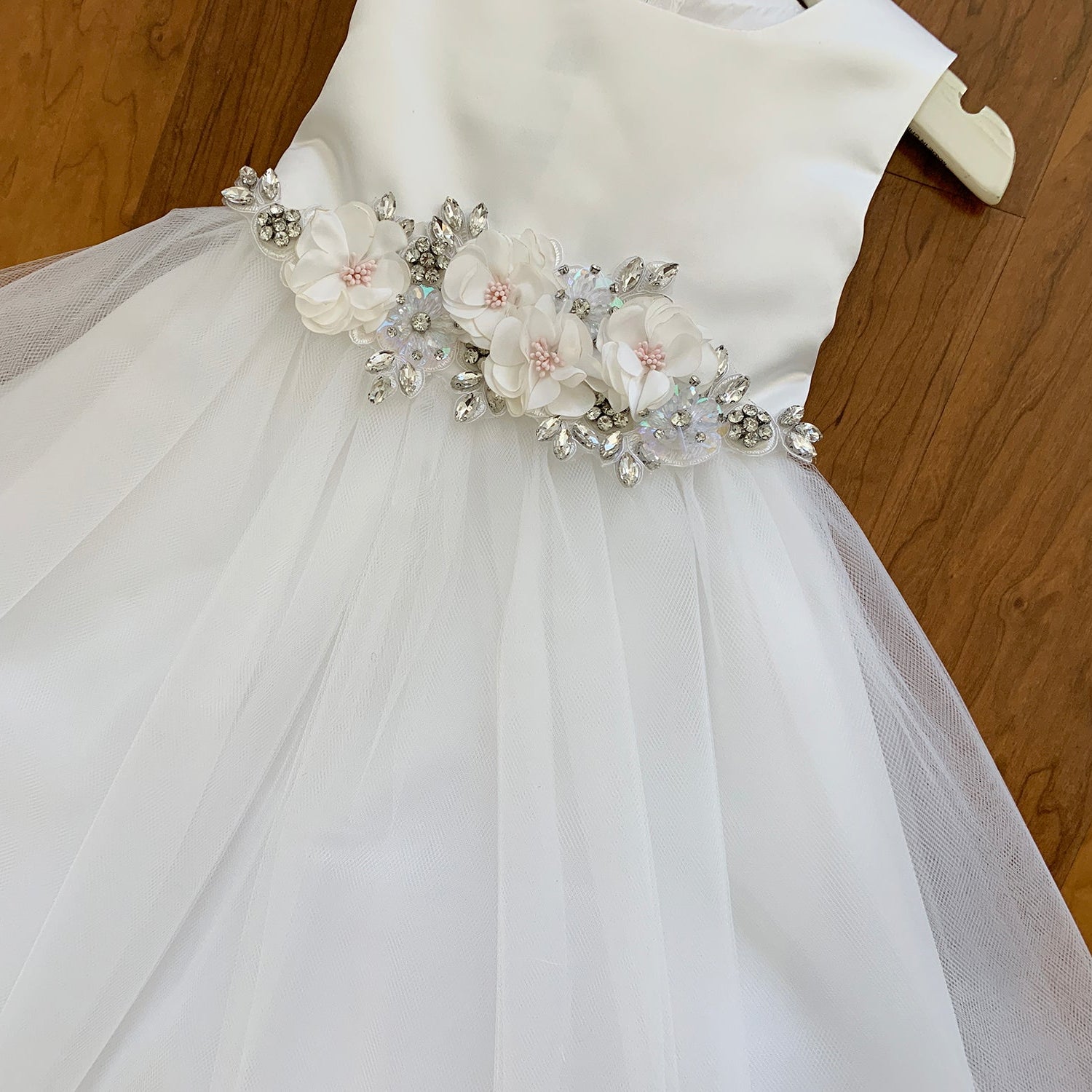 White flower girl satin and tulle flower girl dress with floral embellishments.