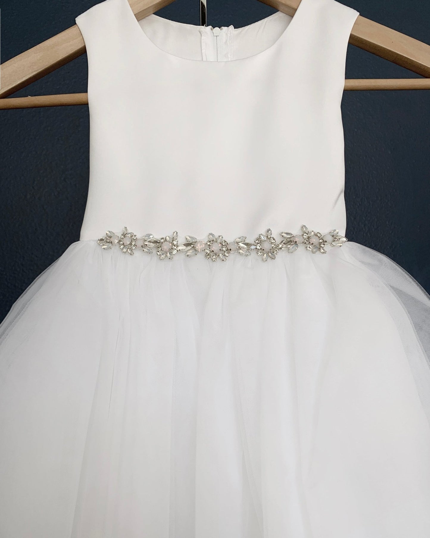 White flower girl dress with a decorative belt.