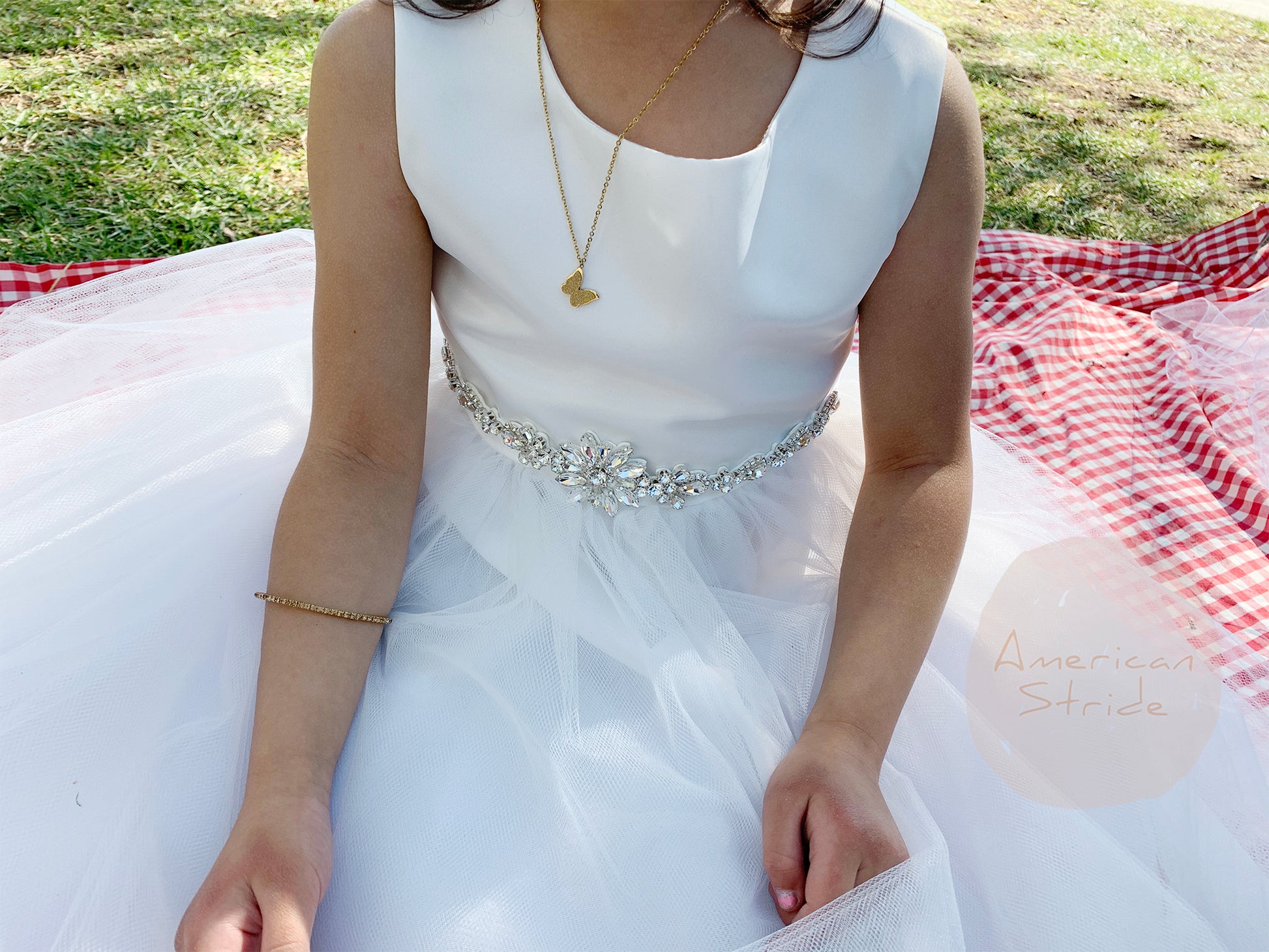 A white flower girl dress with a decorative rhinestone belt.