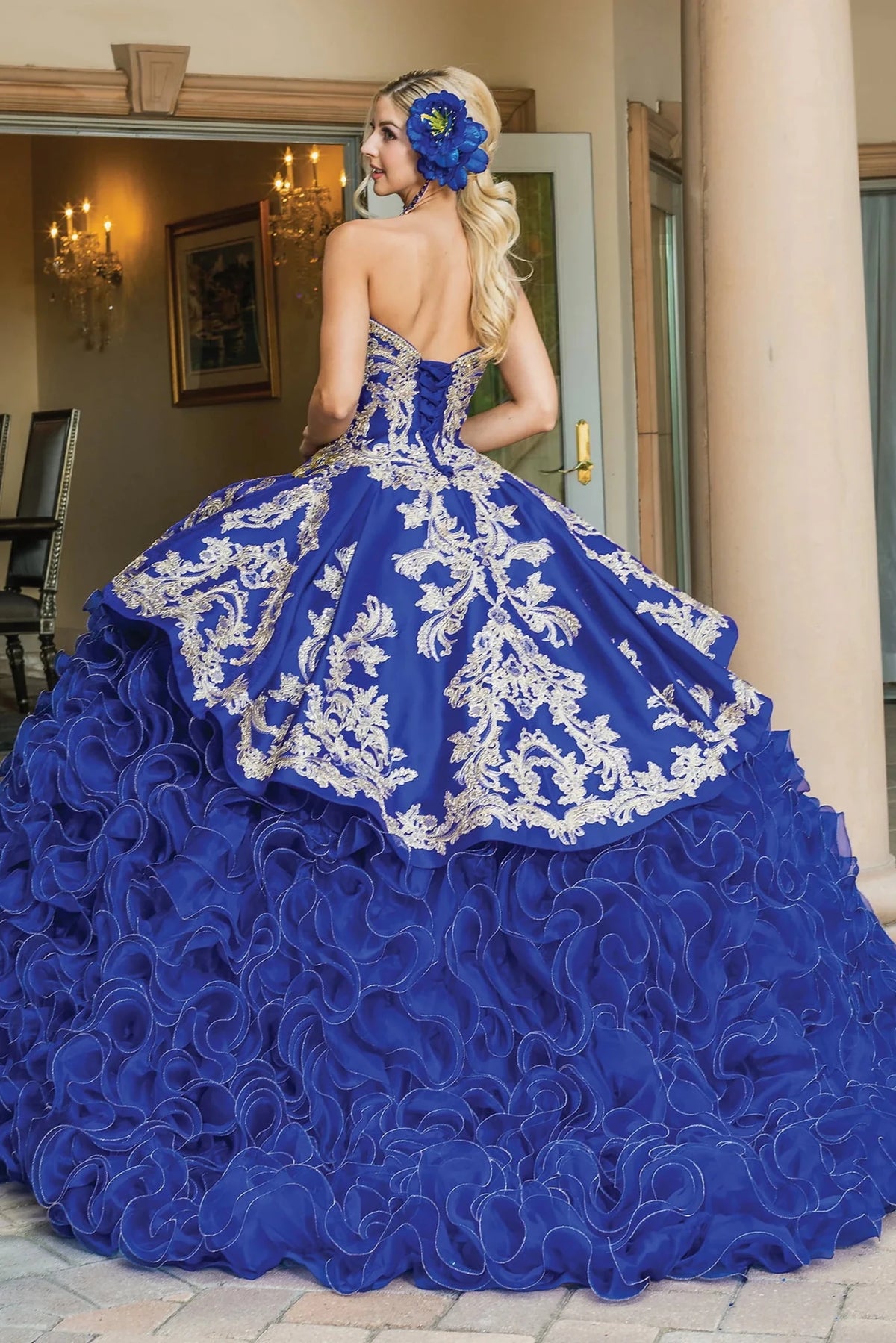 Back view of a Royal Blue quinceañera gown showing lace-up back and cascading organza ruffle skirt