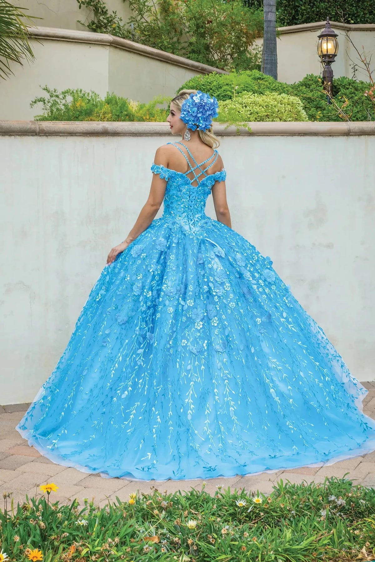 Back view of a Bahama Blue quinceañera gown showing lace-up back, embroidered tulle skirt, and floral appliqués
