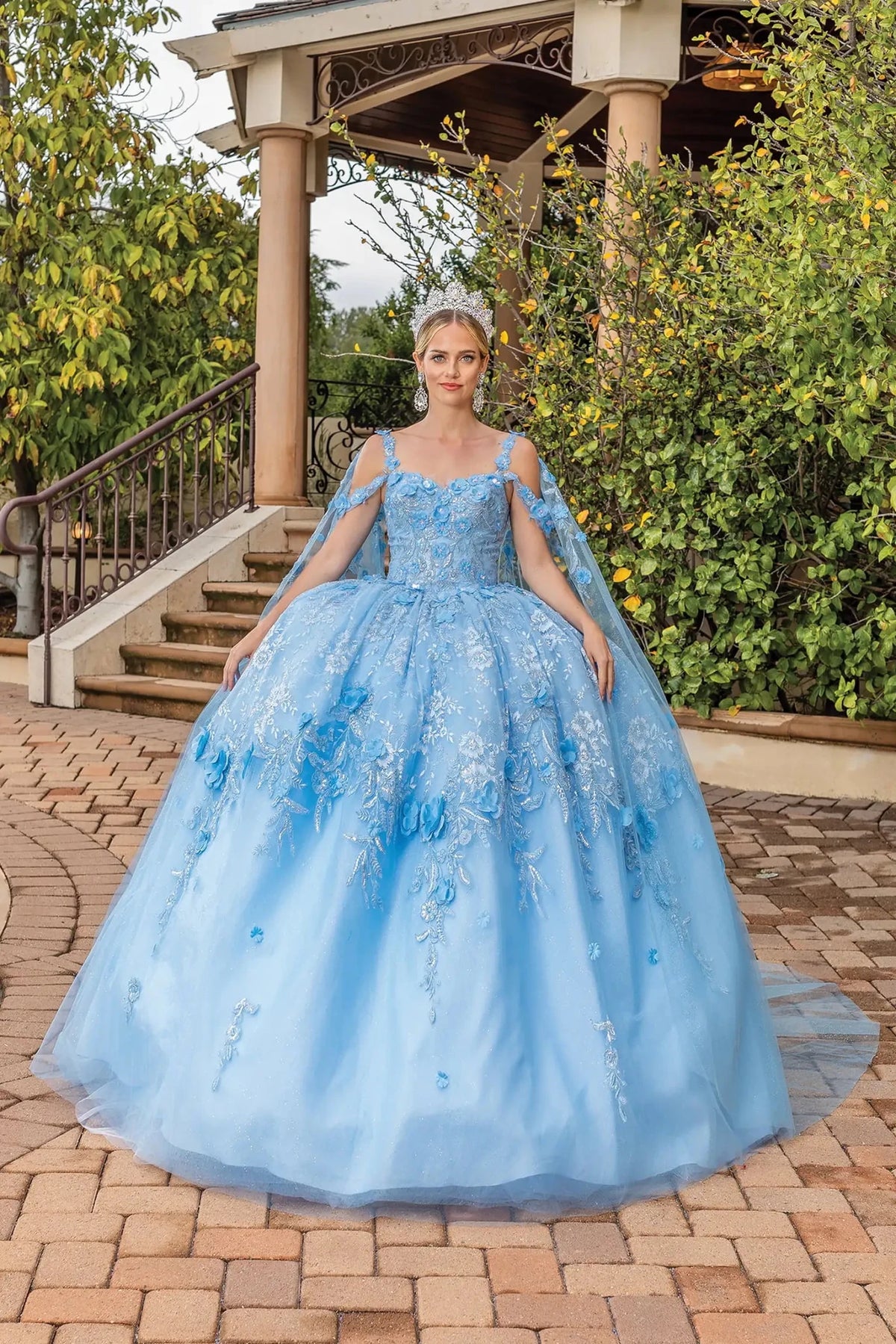 Front view of a Bahama Blue quinceañera gown with illusion neckline, cap sleeves, embellished bodice, and layered tulle skirt