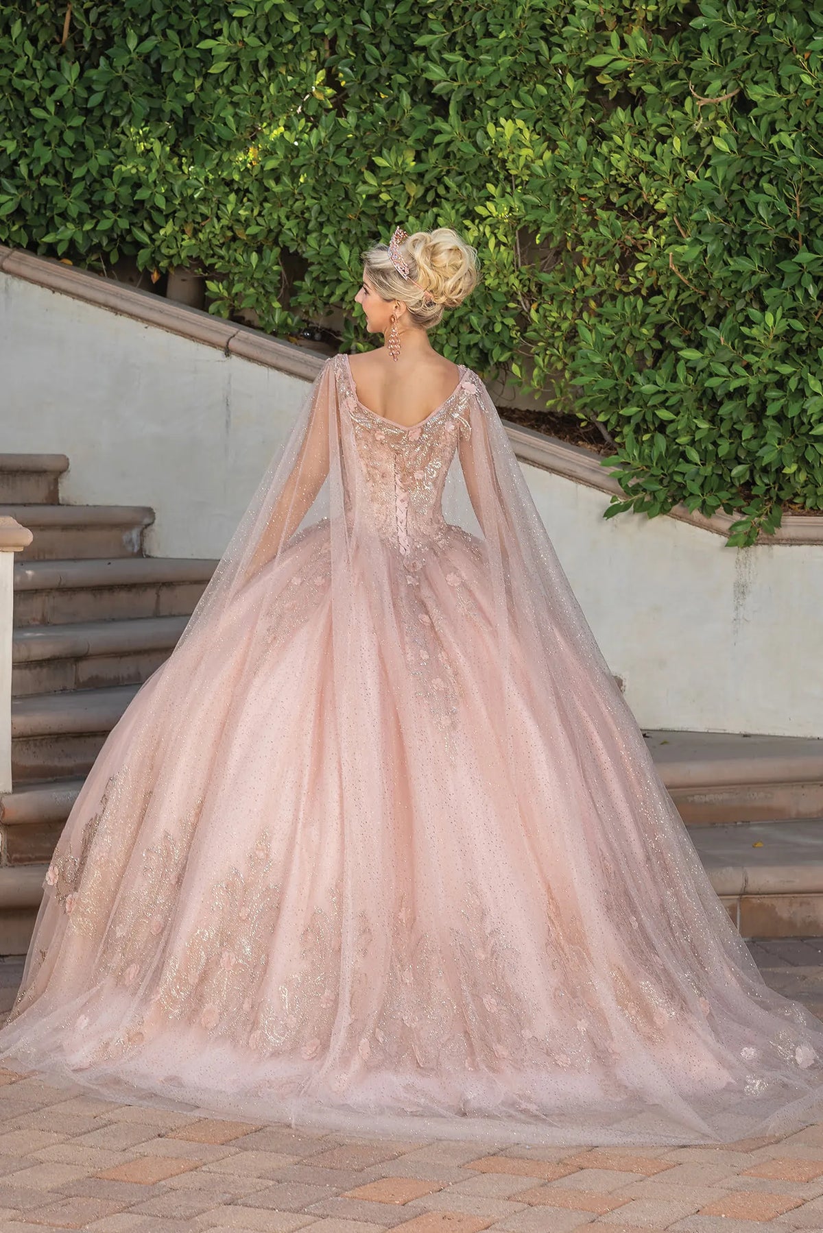 Revealing a lace-up back framed by embroidered shoulder accents, this Rose Gold quinceañera ball gown is shown from the back.