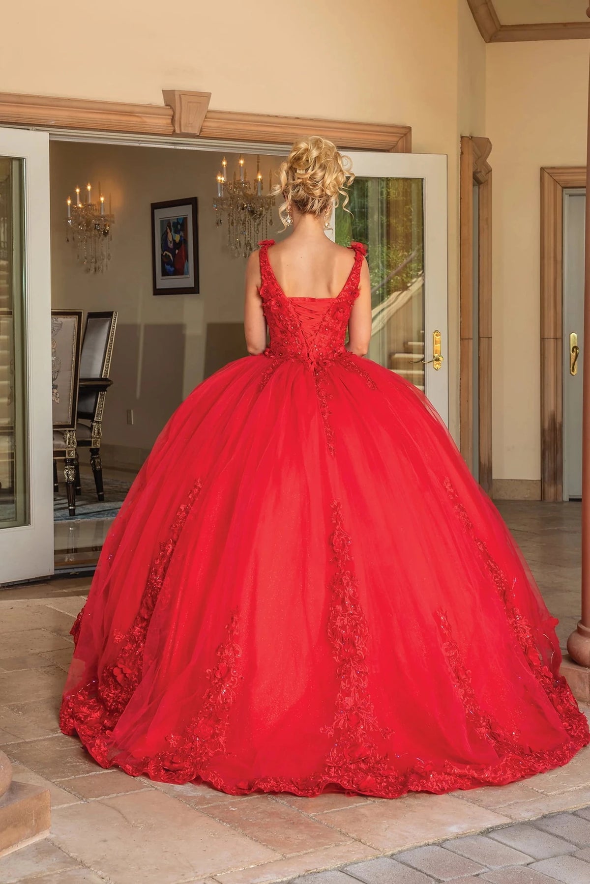 Back view of a Red quinceañera gown showing lace-up back, voluminous full skirt, and embroidered lace